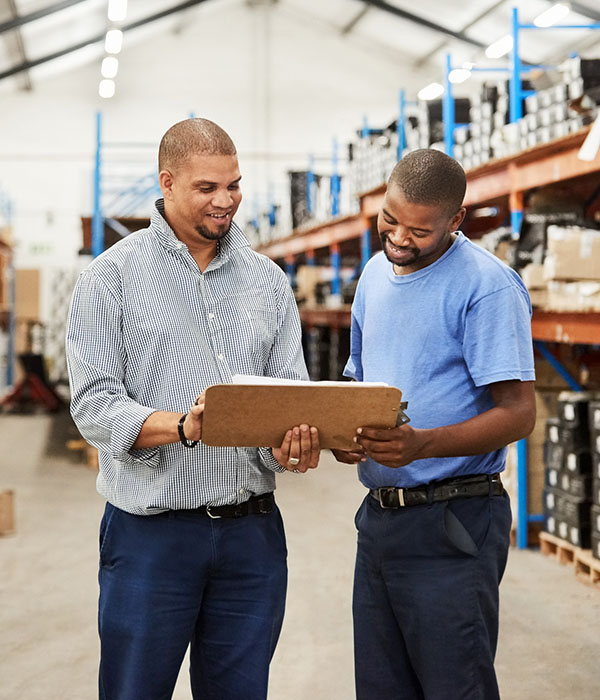 Two male warehouse coworkers discussing over inventory